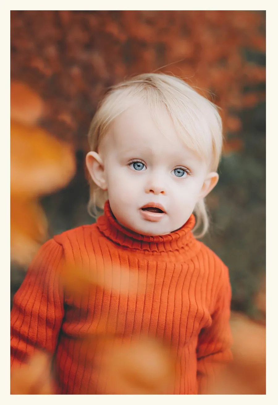 Litet barn i orange kläder under höstlig barnfotografering av Alnwick Photo
