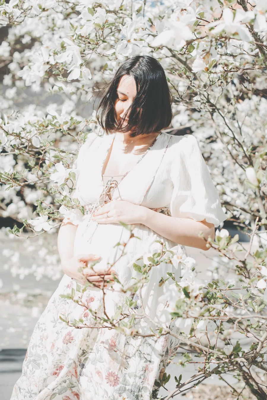 Gravid kvinna bland vita blommor under mjuk gravidfotografering av Alnwick Photo